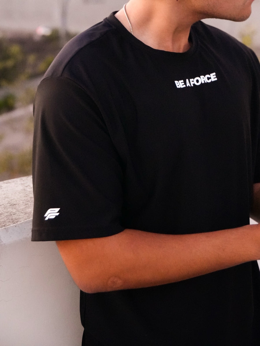 Person wearing a black t-shirt with 'BE A FORCE' text, standing outdoors, black