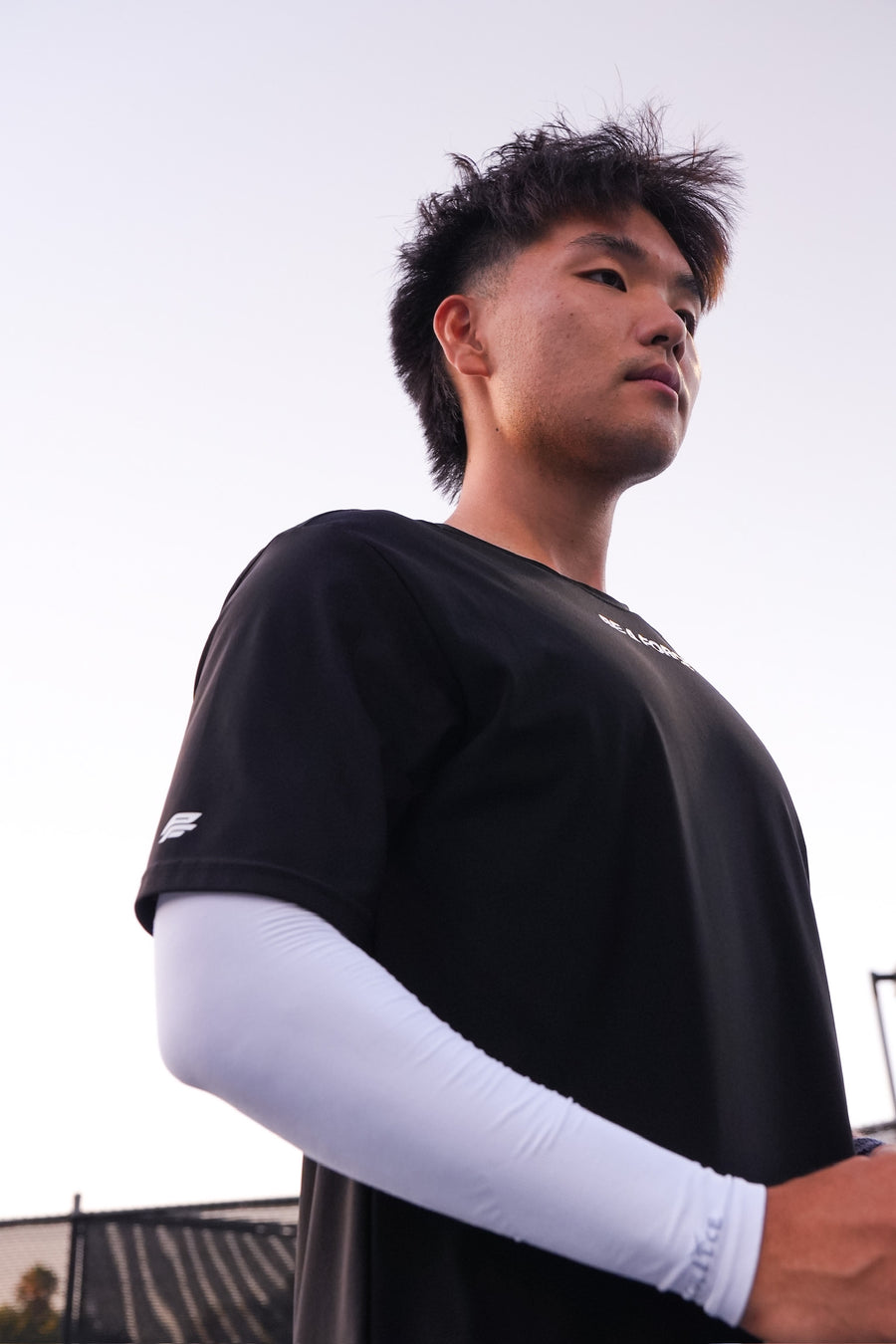 Person wearing a black shirt with white sleeves against a light background, black