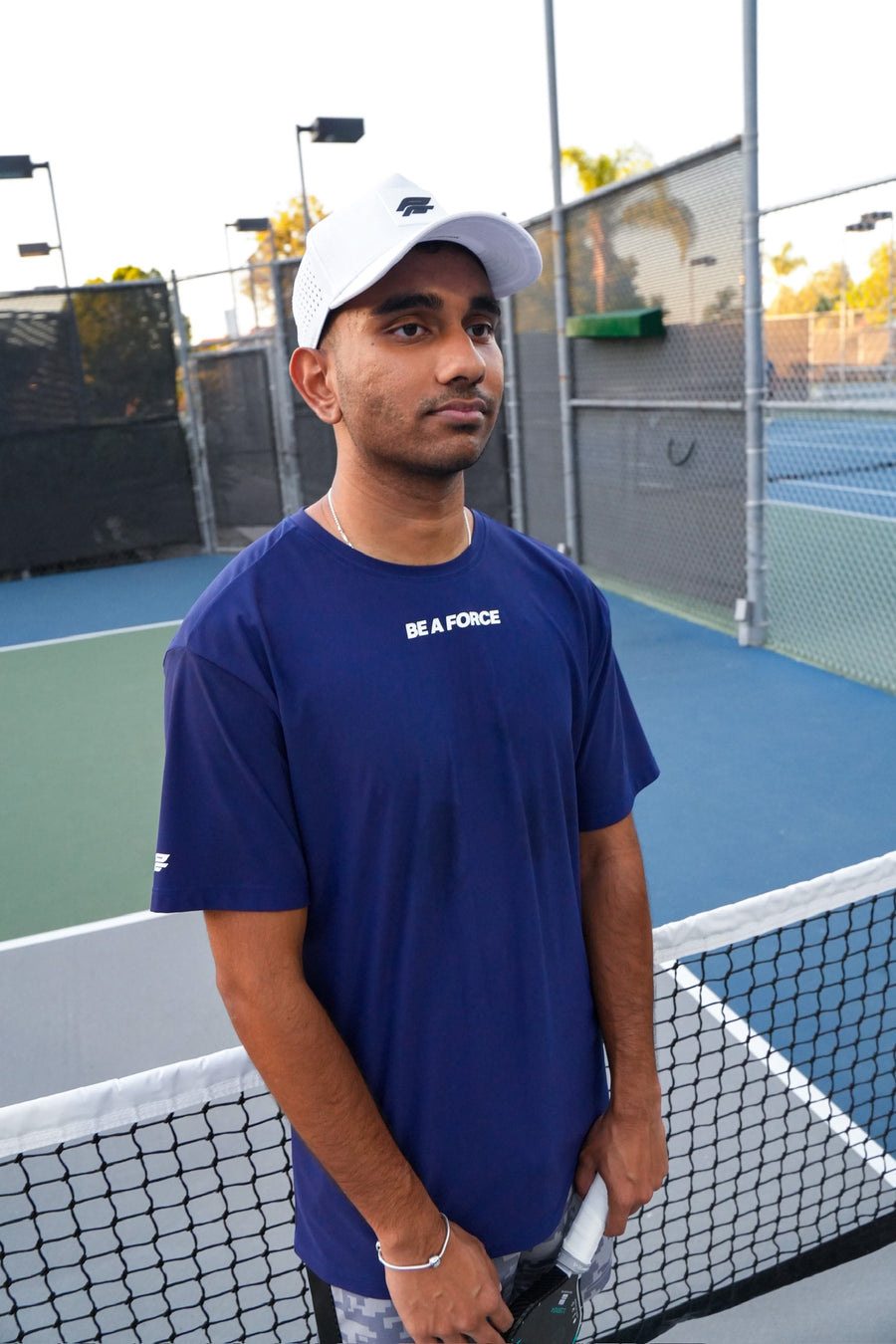 Man in a blue t-shirt with text on a tennis court, navy