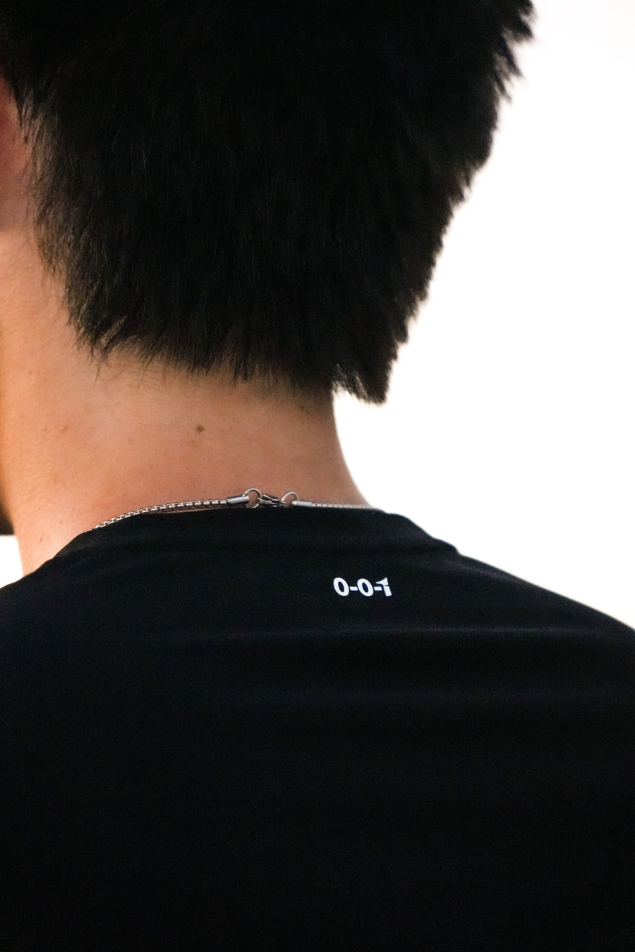 Person wearing a black shirt with a logo on the back against a white background, black