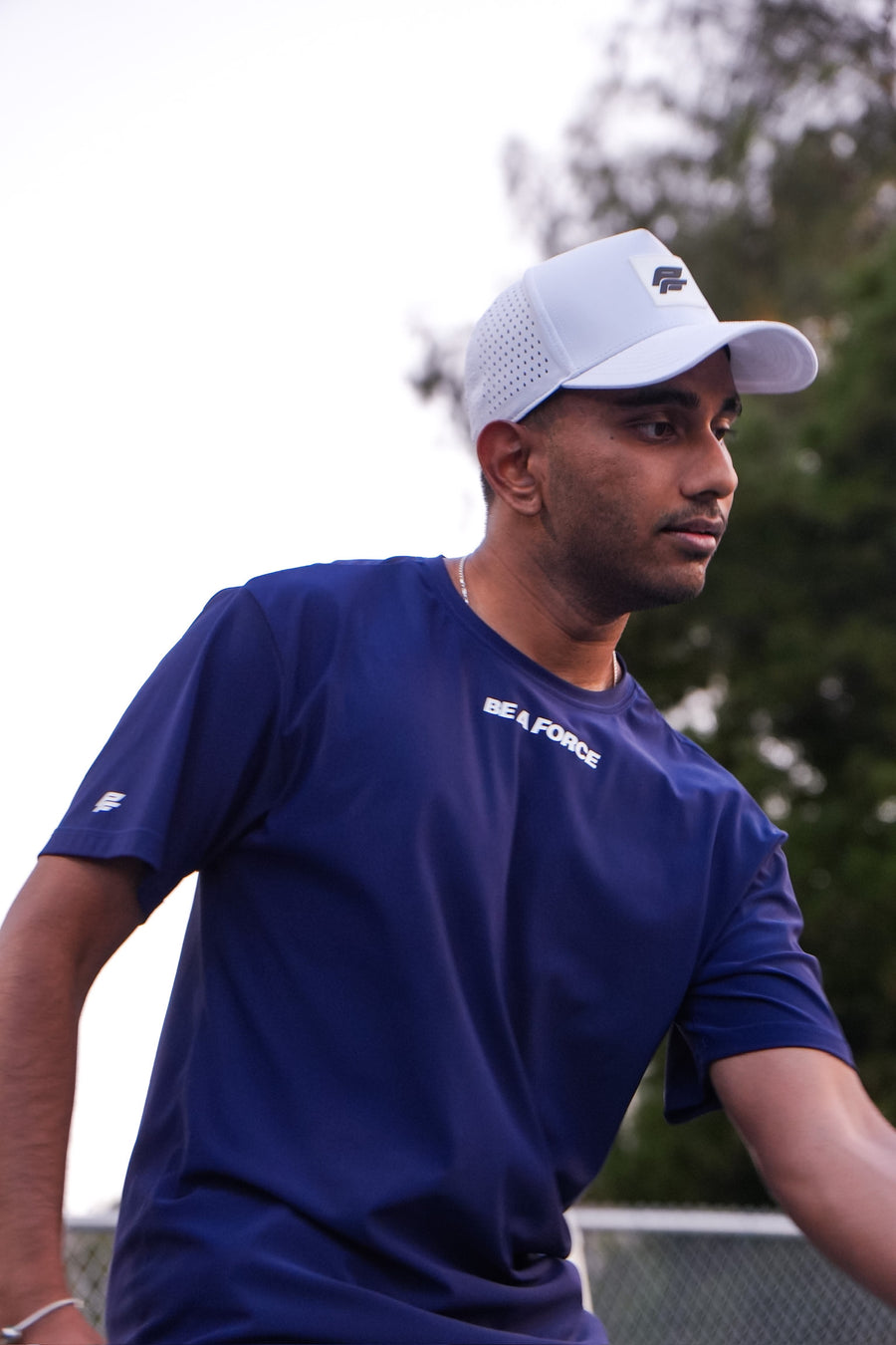 Man wearing a blue 'US Navy' t-shirt and white cap outdoors, navy