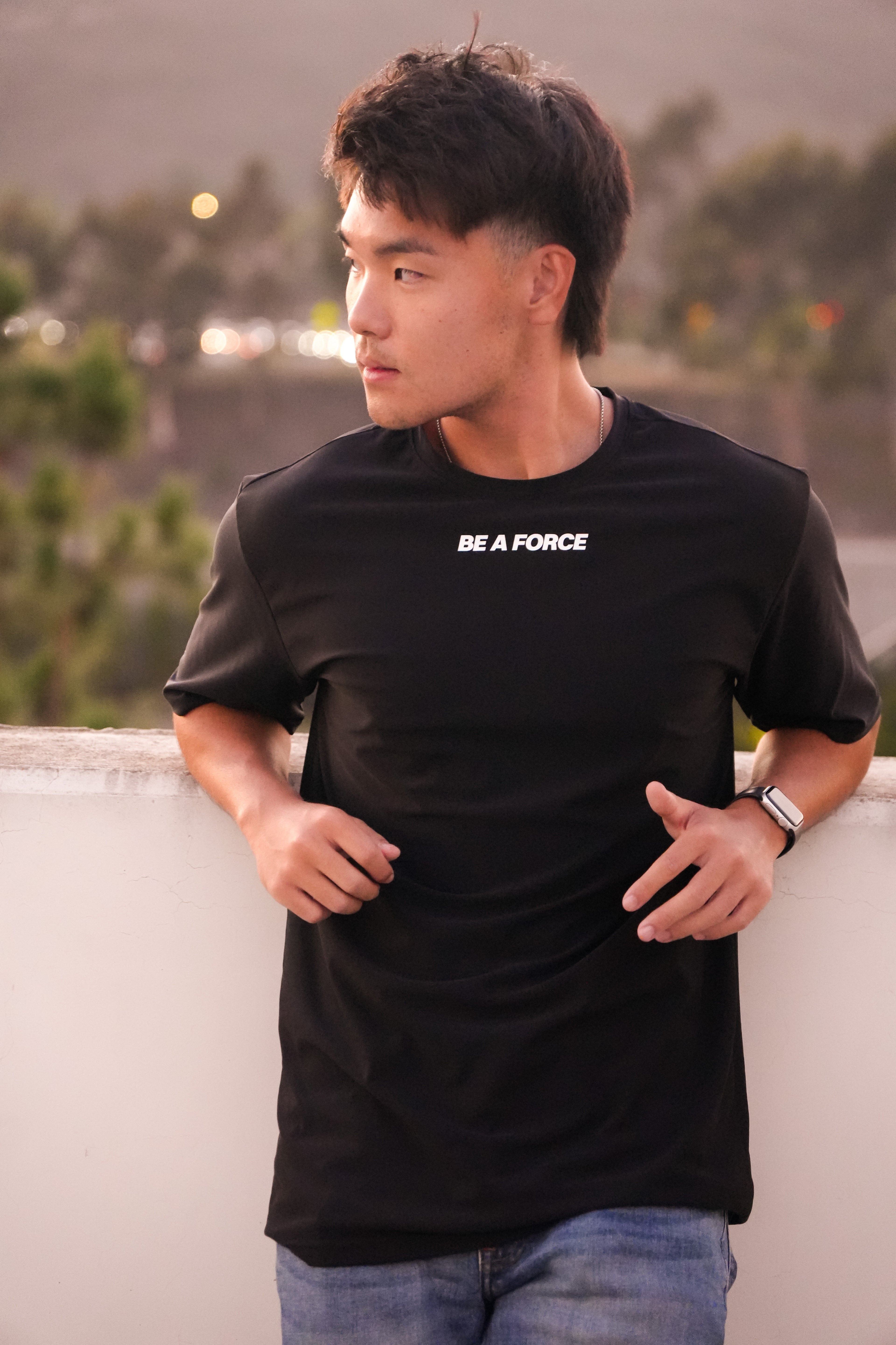 Man wearing a black t-shirt with 'BE A FORCE' text, standing outdoors, black