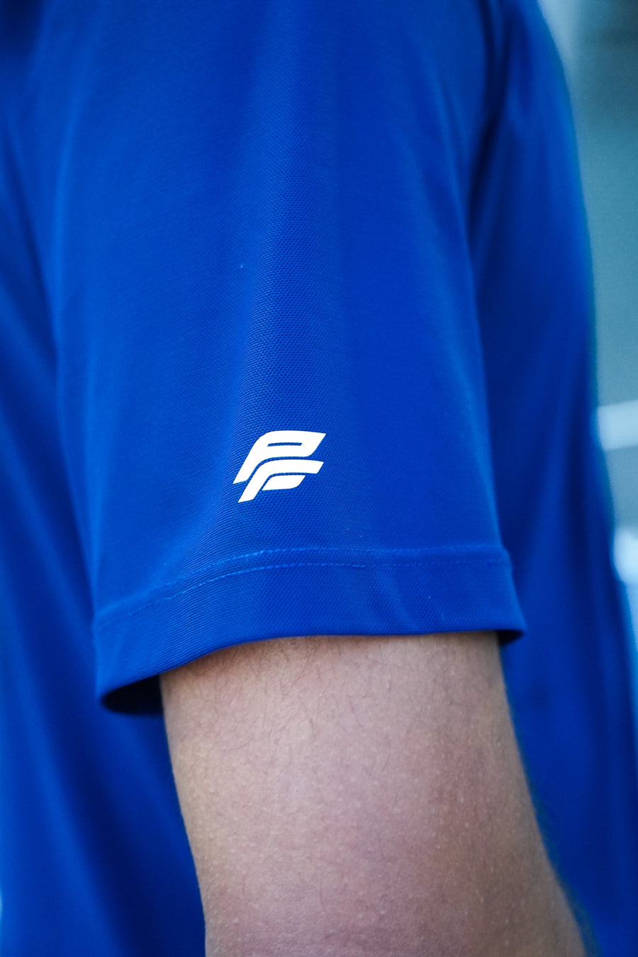 Close-up of a blue shirt with a white logo on a blurred background, navy